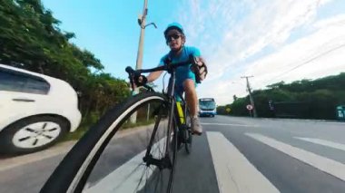 Mavi ekipmanlı bir adam, şehir bölgesinde her türlü ulaşım için tehlikeli bir çevrede bisiklet sürüyor.