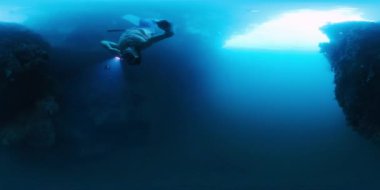 Freediver 'ın görüntüsü. Serbest yüzücü adam meşaleyle su altında yüzüyor ve Endonezya 'nın Batı Papua bölgesini keşfediyor.