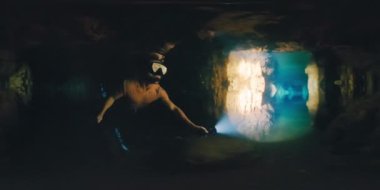 Mağarada yüzen serbest dalgıcın görüntüsü. Serbest yüzücü adam meşaleyle suyun altında yüzüyor ve Batı Papua bölgesi Raja Ampat, Endonezya 'daki sarkıtlarla mağarayı keşfediyor.