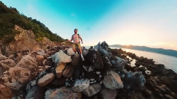 穿着休闲装的渔夫拿着钓竿在滑溜的岩石海岸上行走 差点跌到岩石上 — 图库视频影像
