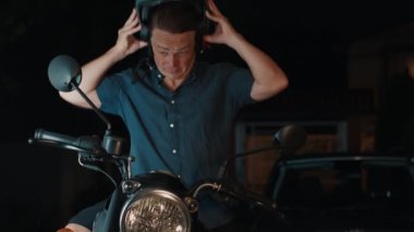 Yorgun üzgün adam motosiklette oturur ve kaskını çıkarır.