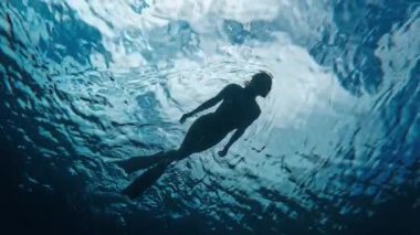 Denizde yüzen kadının sualtı görüntüsü.