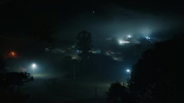 Evlerin uzak ışıklarıyla sisli bir vadi.