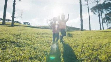 Çocuklar gün batımında yeşil yemyeşil çayırlarda koşar.