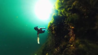 Adam dipte otla göle dalıyor. Batı Papua, Endonezya. Freediver gölde yüzer.