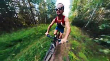 Bisikletçi düşüyor. Genç adam kırsal bir orman yolunda bisiklet sürüyor ve düşüyor.