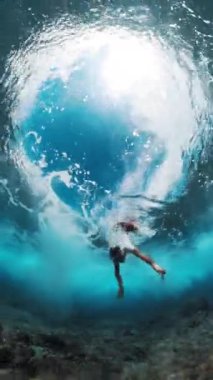 Maskeli adam okyanus dalgalarının altında dalıyor.