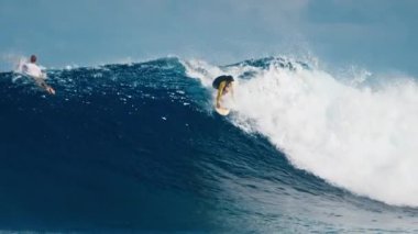Deneyimli sörfçü, Maldivler 'in Kuzey Atolleri' ndeki ünlü Sultanlar sörf noktasında dev, çift yönlü okyanus dalgaları sürüyor.