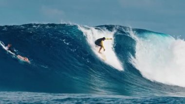 Deneyimli sörfçü, Maldivler 'in Kuzey Atolleri' ndeki ünlü Sultanlar sörf noktasında dev, çift yönlü okyanus dalgaları sürüyor.