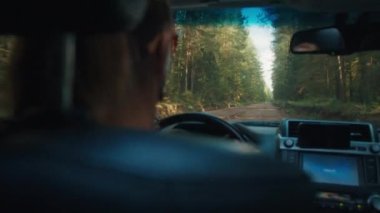 Kadın, yaz aylarında ormanda asfaltsız yolda direksiyon sallar.