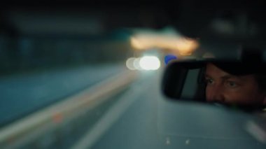 Aynadaki erkek sürücünün yansımasıyla bulanık yol manzarası
