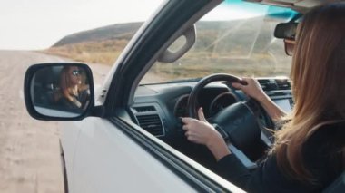 Modern beyaz kadın engebeli kırsal bir yolda 4x4 'lük arabayı yavaşça sürüyor.