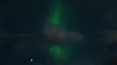 Aurora Borealis, doğal, gerçek hız görüntüsü. Gece gökyüzünde bazı bulutlar ve yıldızlarla kuzey ışıkları. Gökyüzünde bulutlarla şekillenen yeşil kuzey ışıklarının gürültülü bir görüntüsü.