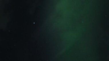 Aurora Borealis, doğal, gerçek hız görüntüsü. Gece gökyüzünde bazı bulutlar ve yıldızlarla kuzey ışıkları. Gökyüzünde bulutlarla şekillenen yeşil kuzey ışıklarının gürültülü bir görüntüsü.