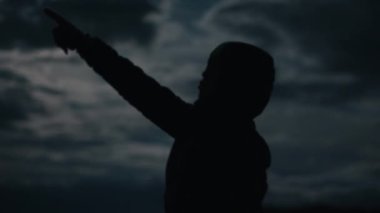 Gece gökyüzünde izleyen kişinin silueti.