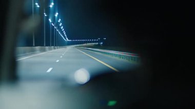 Gece yolculuğu. Aydınlatılmış boş otoyolda geceleyin direksiyon sallayan kişi. Sürücünün otobanda araba sürüşünün iç görüntüsü.