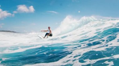 Genç sörfçü çocuk dalgada sörf yapıyor ve spreyle keskin bir dönüş yapıyor. Maldivlerde tropik sörf