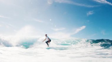 Genç sörfçü çocuk dalgada sörf yapıyor ve spreyle keskin bir dönüş yapıyor. Maldivlerde tropik sörf