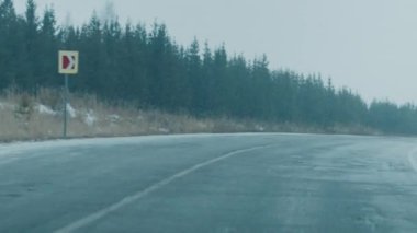 Arabalı kış yolu. Kar fırtınası sırasında üzerinde hareket eden arabalar olan asfalt yol boyunca kamera hareket eder.