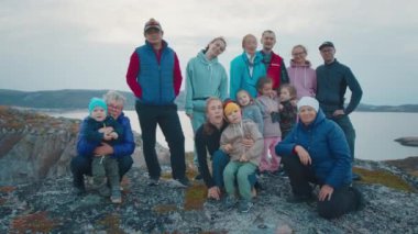 Yürüyüşçülerden oluşan bir grup. Çocuklu geniş bir aile tepede durup kameraya bakar.