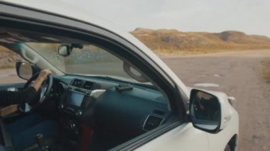 Genç kadın engebeli asfaltsız bir yolda büyük 4x4 'lük arabayı sürüyor.