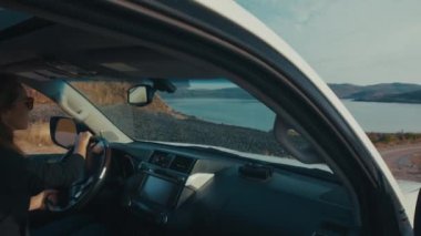 Genç kadın engebeli asfaltsız bir yolda büyük 4x4 'lük arabayı sürüyor.
