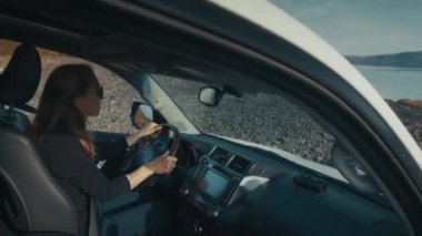 Genç kadın engebeli asfaltsız bir yolda büyük 4x4 'lük arabayı sürüyor.