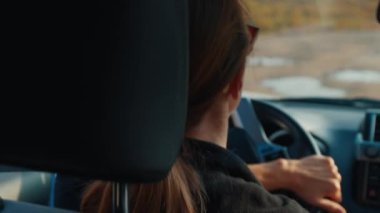 Genç kadın engebeli asfaltsız bir yolda büyük 4x4 'lük arabayı sürüyor.