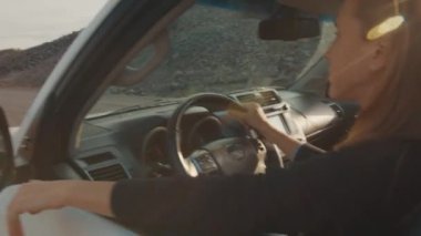 Rahat kadın gündoğumunun tadını çıkarıyor ve engebeli bir yolda büyük 4x4 'lük arabayı sürüyor.