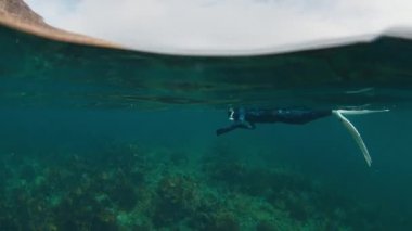 Kuzey Kutbu serbest dalışı. Barents Denizi 'nde mavi kalın dalgıç kıyafetiyle yüzen ve kuzey denizinin güzelliğinin tadını çıkaran genç bir kadın.