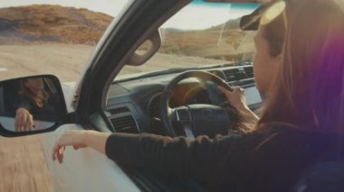 Rahat kadın gündoğumunun tadını çıkarıyor ve engebeli bir yolda büyük 4x4 'lük arabayı sürüyor.