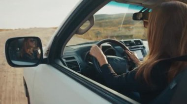 Genç kadın engebeli asfaltsız bir yolda büyük 4x4 'lük arabayı sürüyor.
