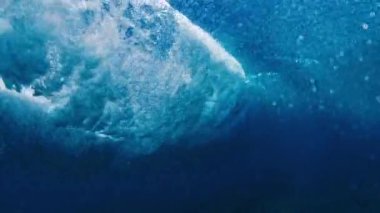 Okyanus dalgası yüzeyde kırılıyor, suyun altından görülüyor. Maldivler