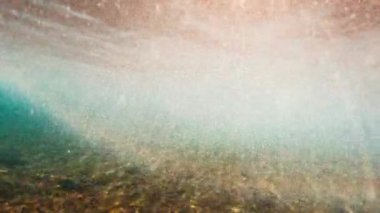 Okyanusun yüzeyine bir dalga çarparken güneş ışığı suyun içinde parlar. Maldivler