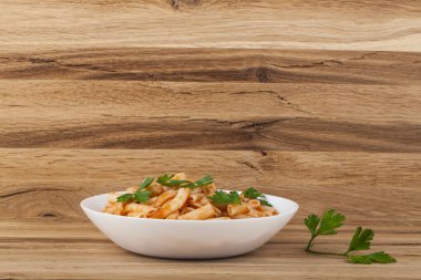 Ahşap arka planda maydanozla süslenmiş tavuklu domates soslu makarna. Metin için boşluk ile.