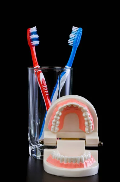 用黑色背景隔离的牙刷和玻璃杯 健康卫生的概念 — 图库照片