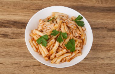 Tahta bir masada maydanozla süslenmiş tavuklu domates soslu makarna. Yukarıdan görüntüle.