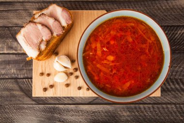 Ahşap zemin üzerinde domuz pastırması, sarımsak ve tüm baharatla bir kase Ukrayna çorbası ve ekmek. Kırmızı pancar, lahana, domates, patates çorbası..