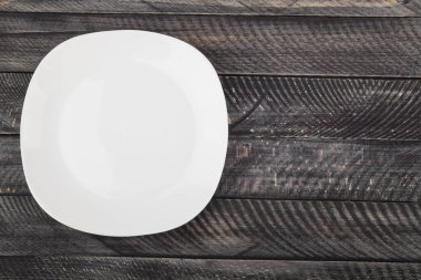 Tahta masadaki beyaz tabak. Üst görünüm.