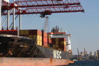 Odessa, Ukraine-202: Logistics terminal sends import-export cargo containers to cargo ship in seaport. Industrial landscape with gantry cranes loading ship at berths of Odessa port, port of Ilyichevsk