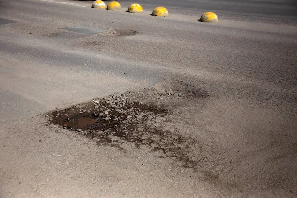 stock image Damaged asphalt road with potholes caused by freezing and thawing cycles during the winter. 