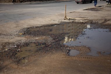 Due to the violation of road construction technology, severe frosts and heavy rains, the asphalt washed out the road and numerous cracks formed