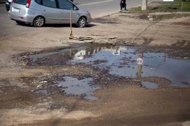 Due to the violation of road construction technology, severe frosts and heavy rains, the asphalt washed out the road and numerous cracks formed