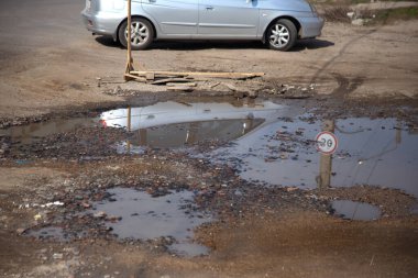 Due to the violation of road construction technology, severe frosts and heavy rains, the asphalt washed out the road and numerous cracks formed