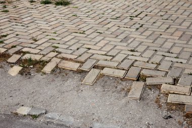 Arka planda kırık kaldırım levhaları ve fayansların arasında yeşil çimenler var. Terk edilme ve kentsel yapının çürüme geçmişi. Eski terk edilmiş yol yüzeyi