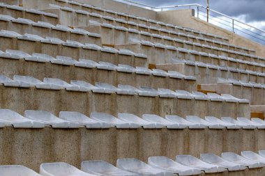 Küçük bir taşra stadyumundaki klasik spor arka koltukları. Futbol taraftarları için tribünlerin merdivenlerindeki boş koltukların arka planı