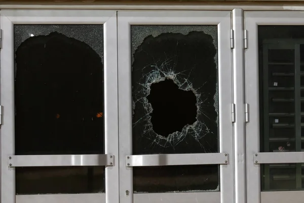a bullet hole in glass is a real bullet hole of a large caliber projectile bullet. Glass door pierced by a bullet during the war, terrorist attack. Broken glass with cracks and a large hole in glass