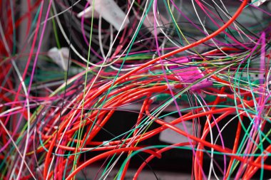 Elektrik dolabına dolanmış kablolar. Elektrik ve ana kablolar birbirine dolanmış. Kavram - güç şebekesinin ayarlanması. Karışık kablolarla dolu elektrik dolabını aç. Elektrik ayarlaması.