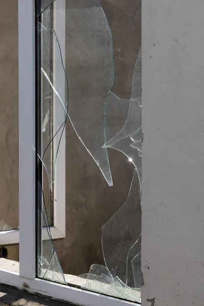 bullet hole in glass is a real bullet hole of a large caliber projectile bullet. Glass door pierced by a bullet during the war, terrorist attack. Broken glass with cracks and a large hole in glass