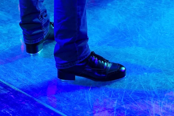 床にアイルランドのダンスのためのストライプや革の靴とステージパンツで動作中の男性の足 床に反射してタップダンスのための黒い作業ブーツ 選択的集中 ステージ上のステップアップ — ストック写真